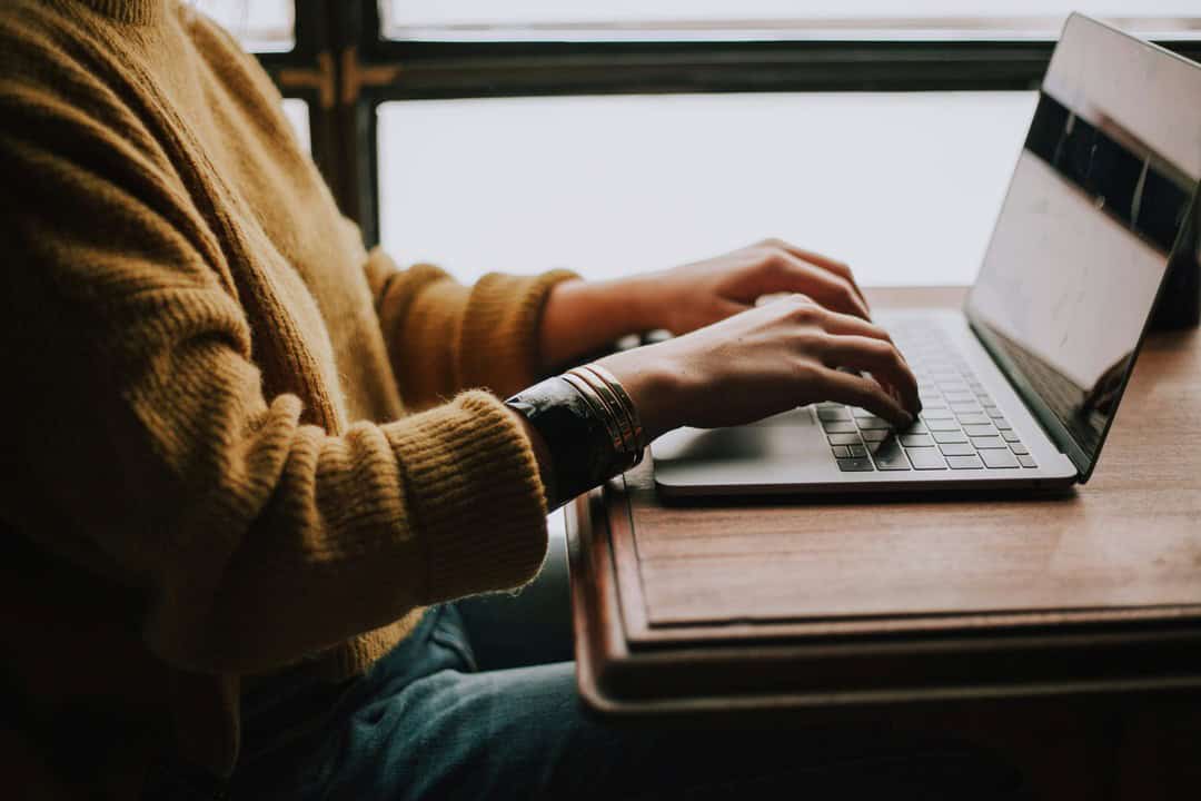 Person typing on laptop at window